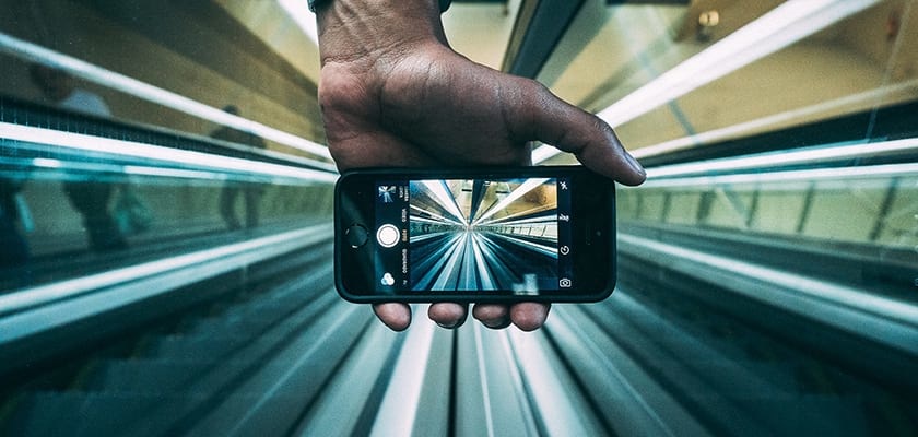 hand holding a cellphone taking a picture of an escalator