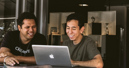 image of two men smiling looking at their computer